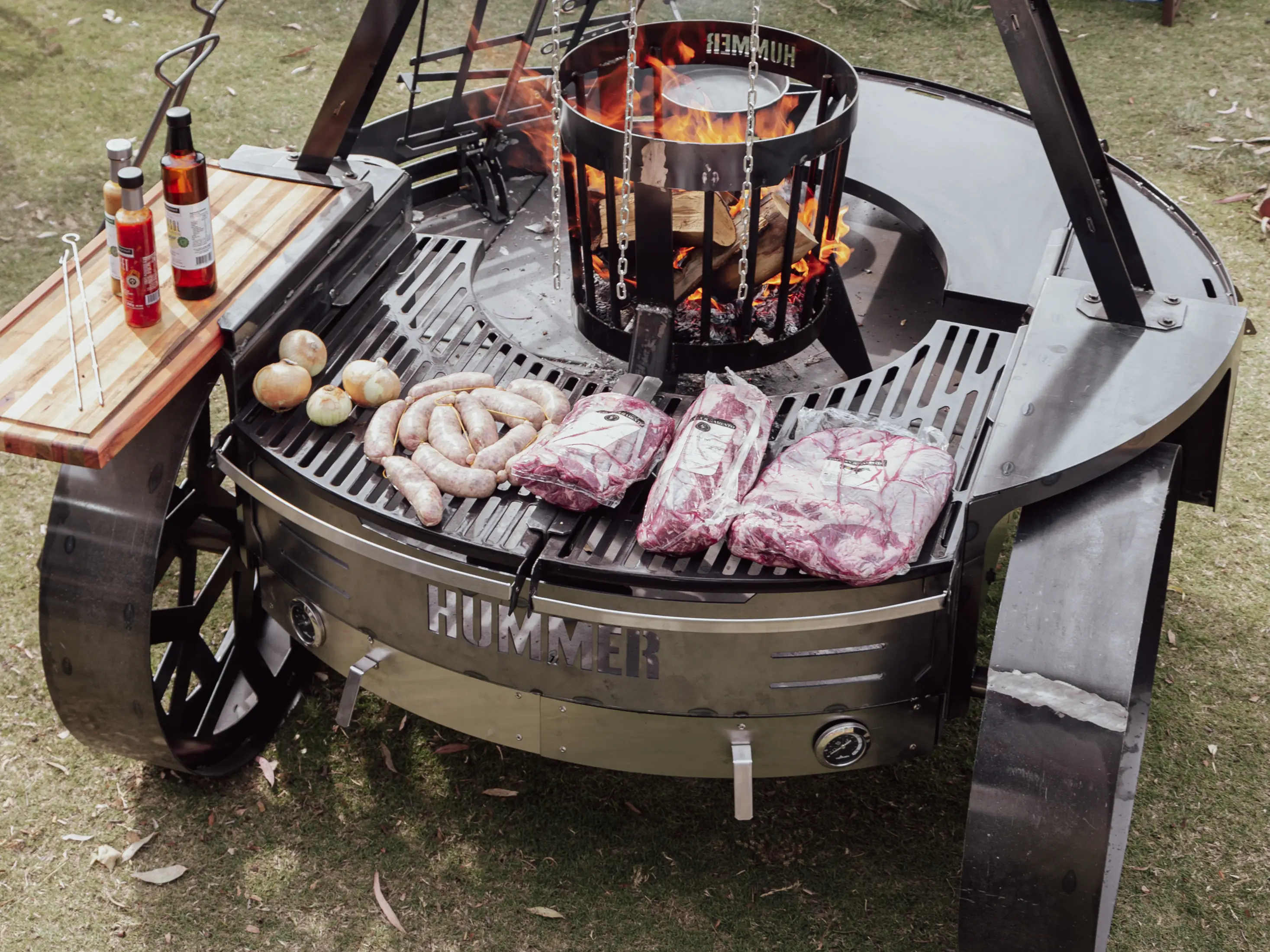 Asador Parrilla a leña Hummer con herraje de acero calado y plancha (deslizables y enlozados), estaca asadora con regulación de inclinación y giro, percha con sobre parrilla, hornos con pirometros, porta provoleteras y tabla lateral