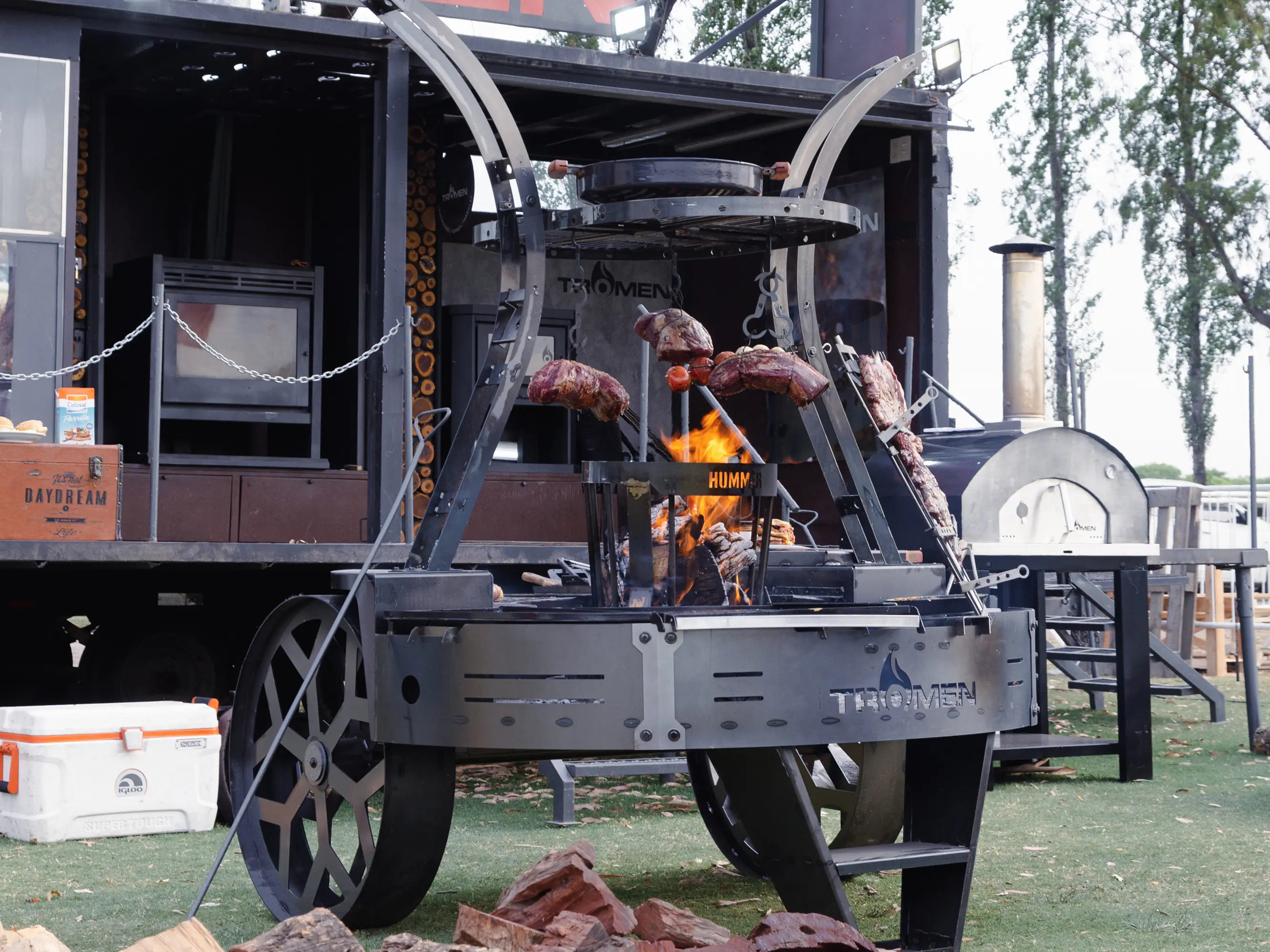 Asador Parrilla a leña Hummer con herraje de acero calado y plancha (deslizables y enlozados), estaca asadora con regulación de inclinación y giro, percha con sobre parrilla, hornos con pirometros, porta provoleteras y tabla lateral